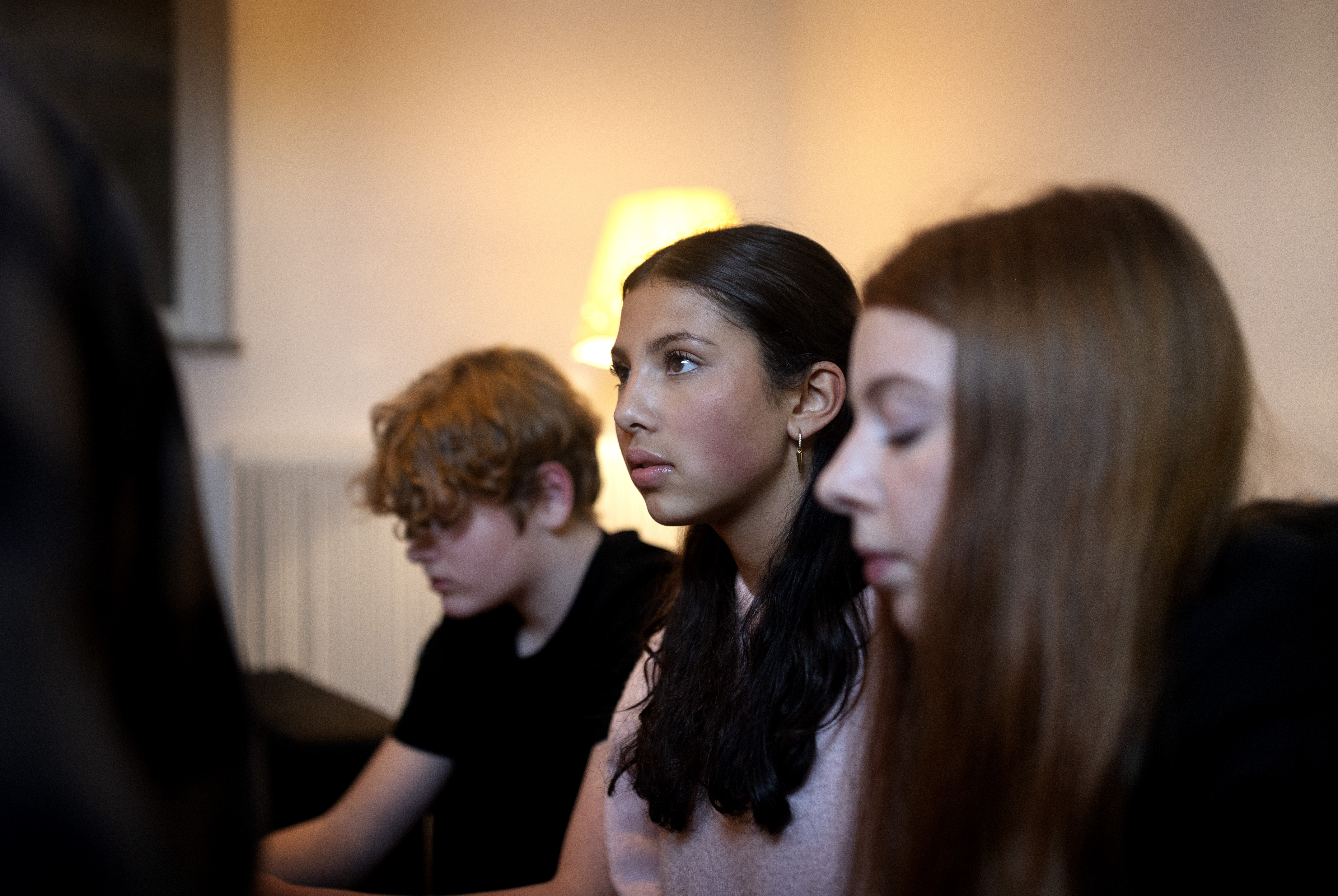 Närbild på tre ungdomar som sitter bredvid varandra inomhus.