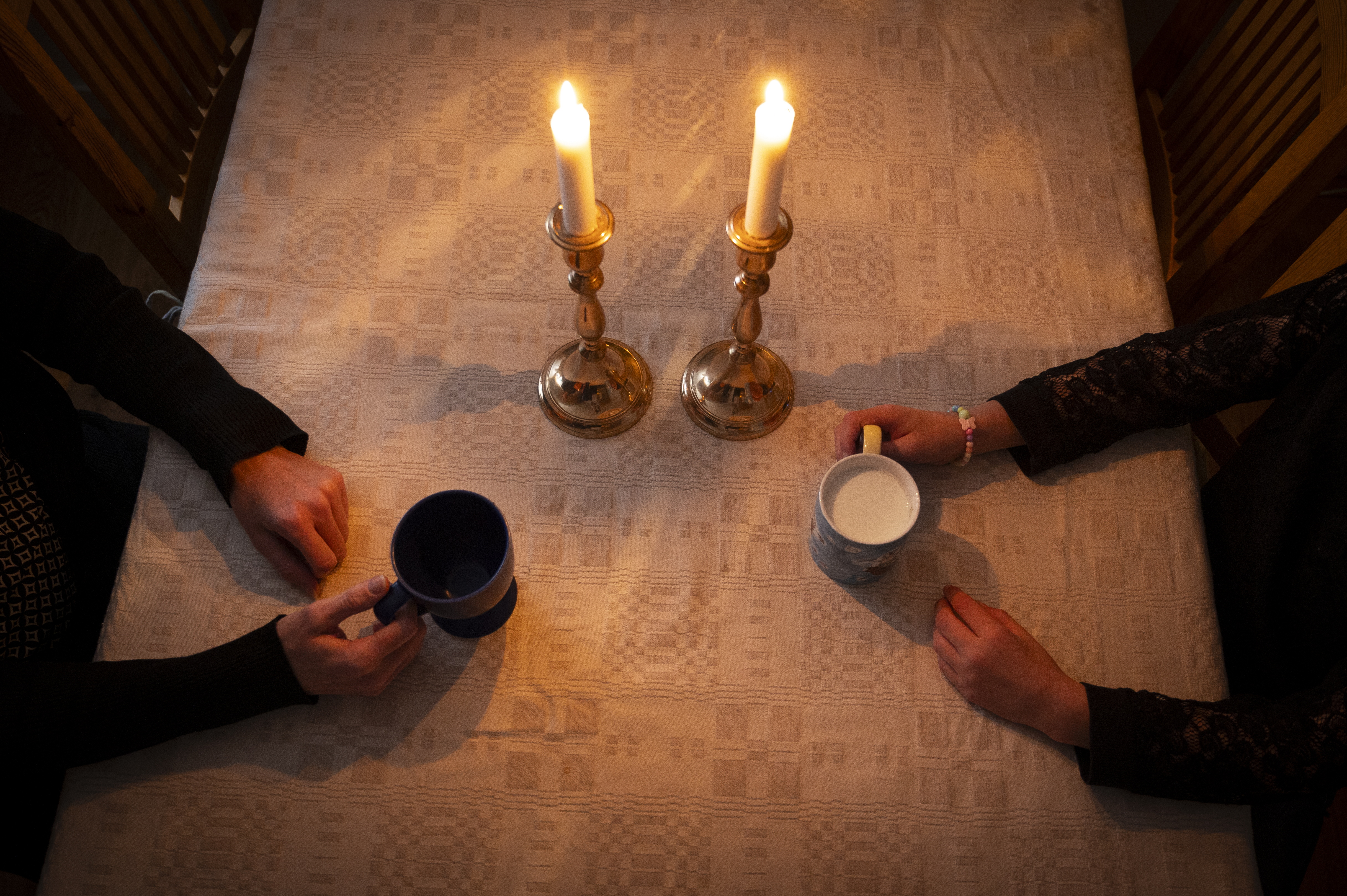 Fika med samtal mellan två personer i hemmamiljö. Levande ljus på bordet.