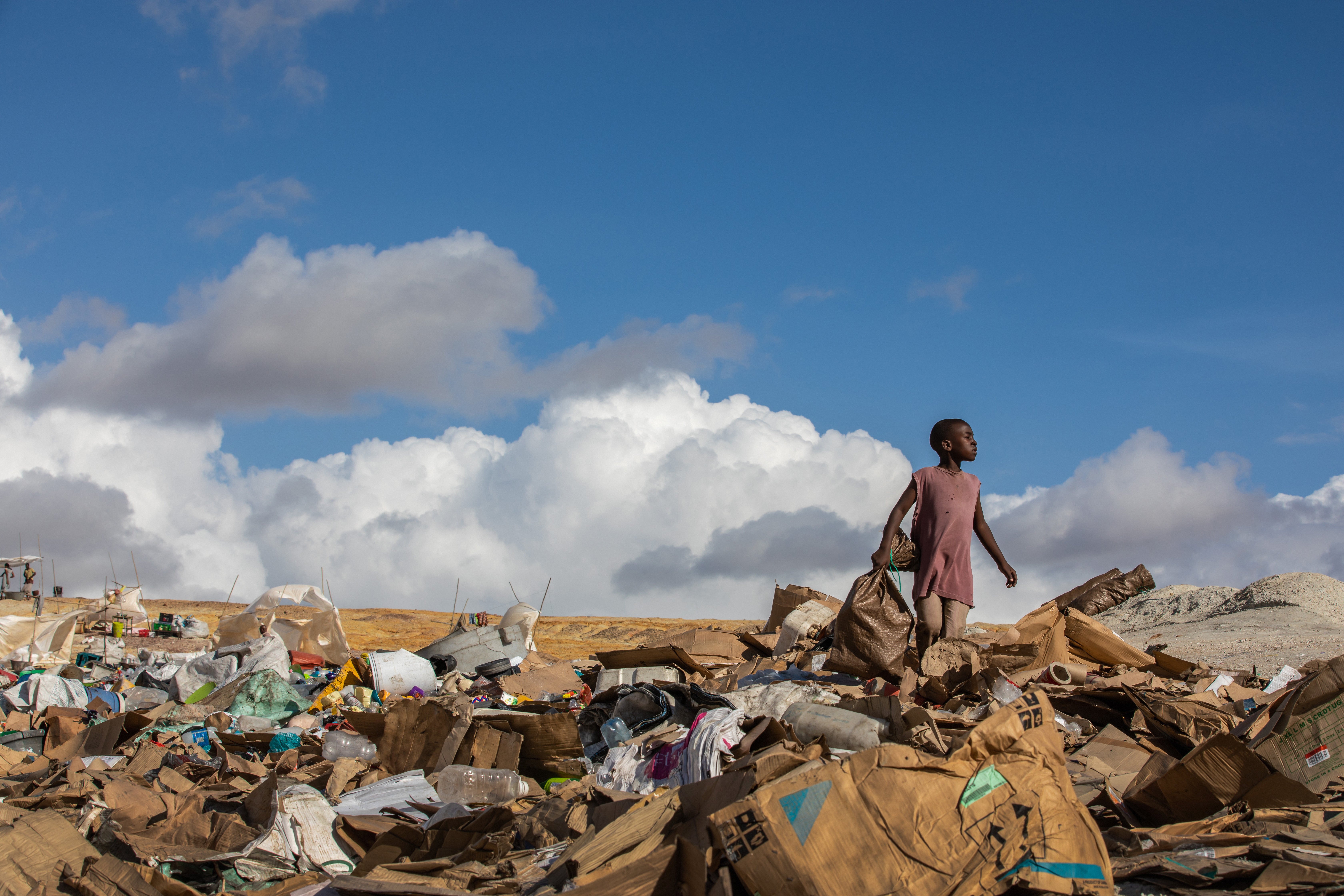 Pojke står på en soptipp. Han tittar drömmande bortåt. 