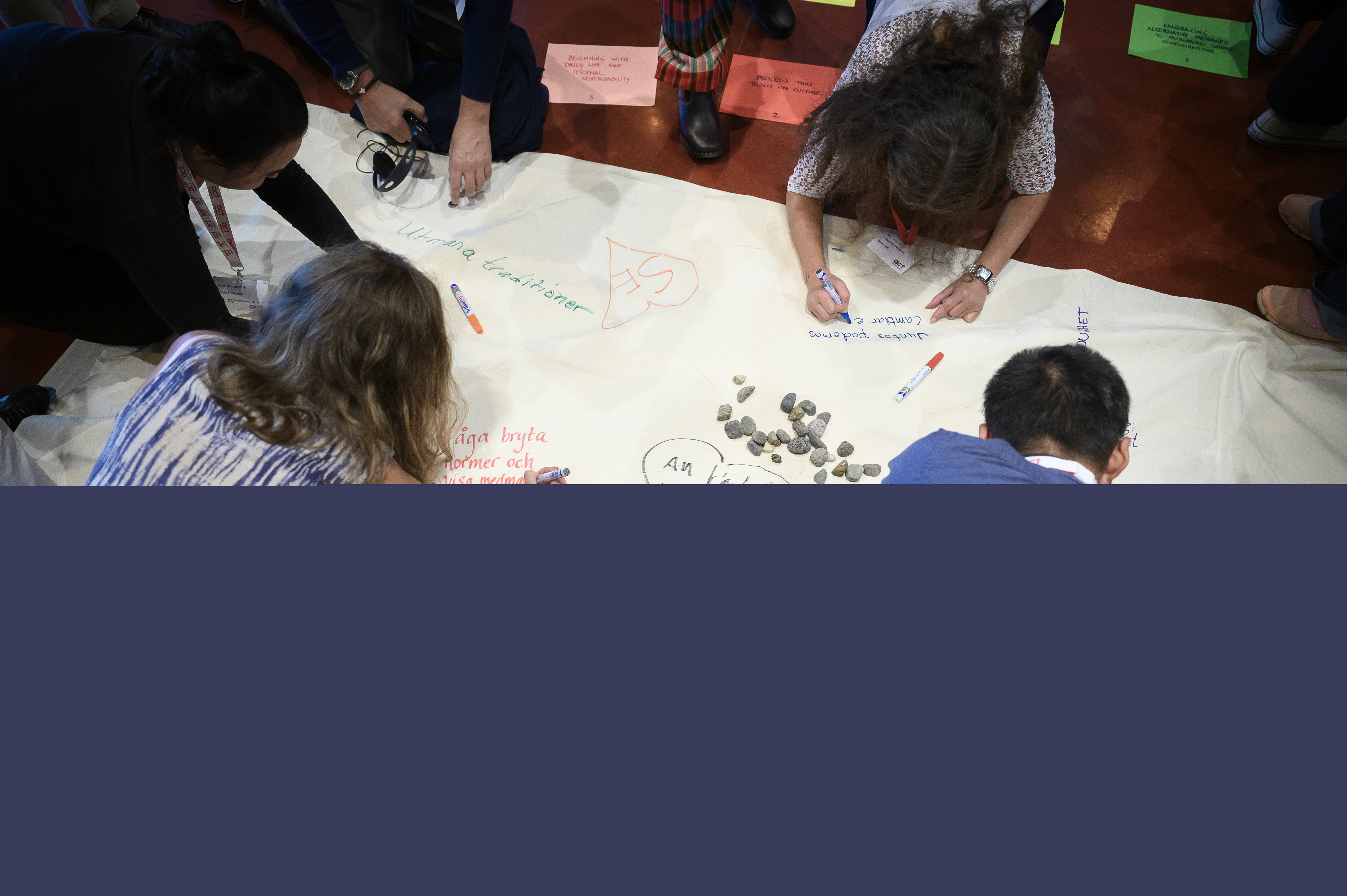 Workshop. Några personer skriver på en stor duk på golvet.