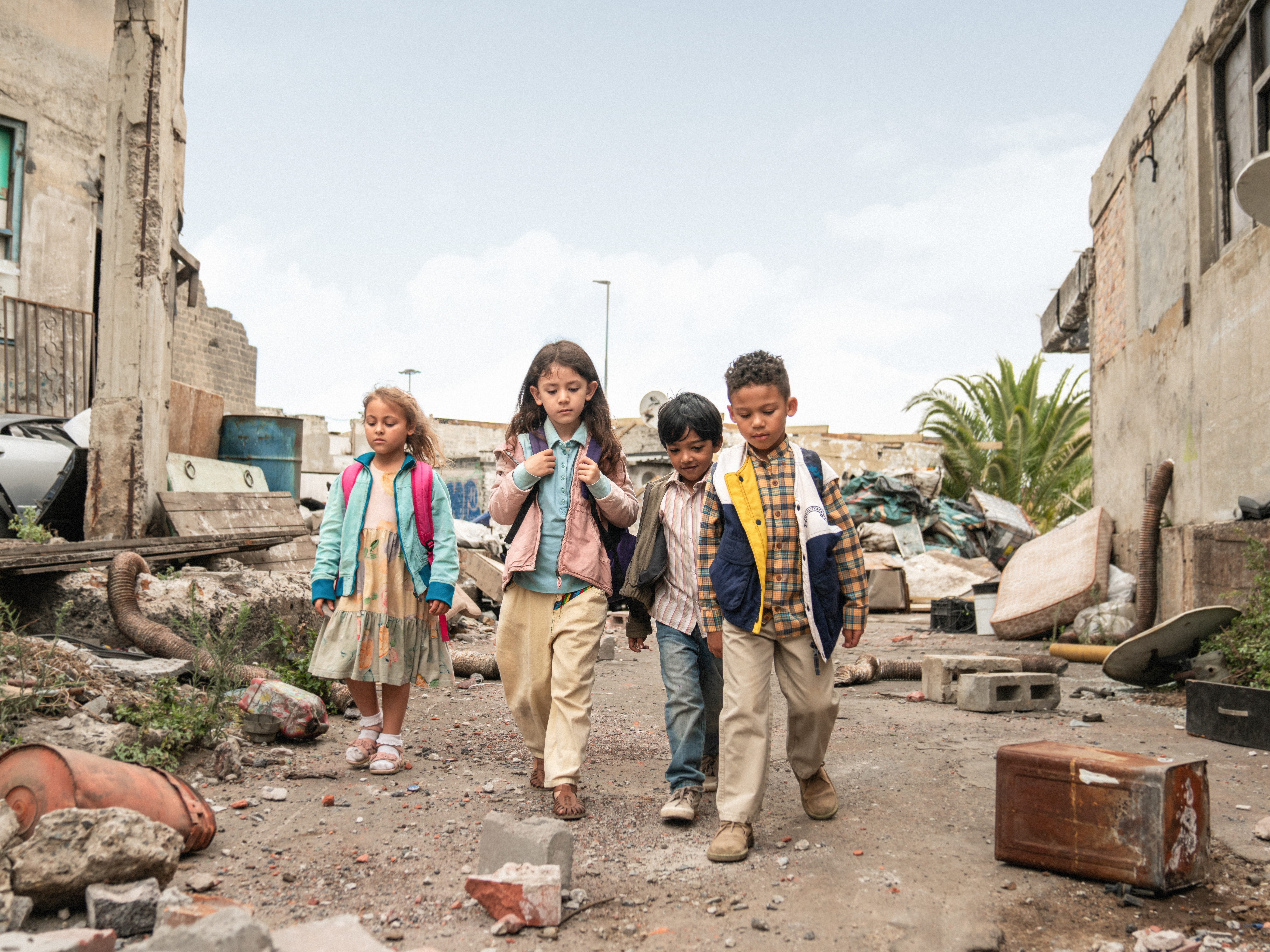 Fyra barn påväg till skolan. De går på en sönderskjuten väg.