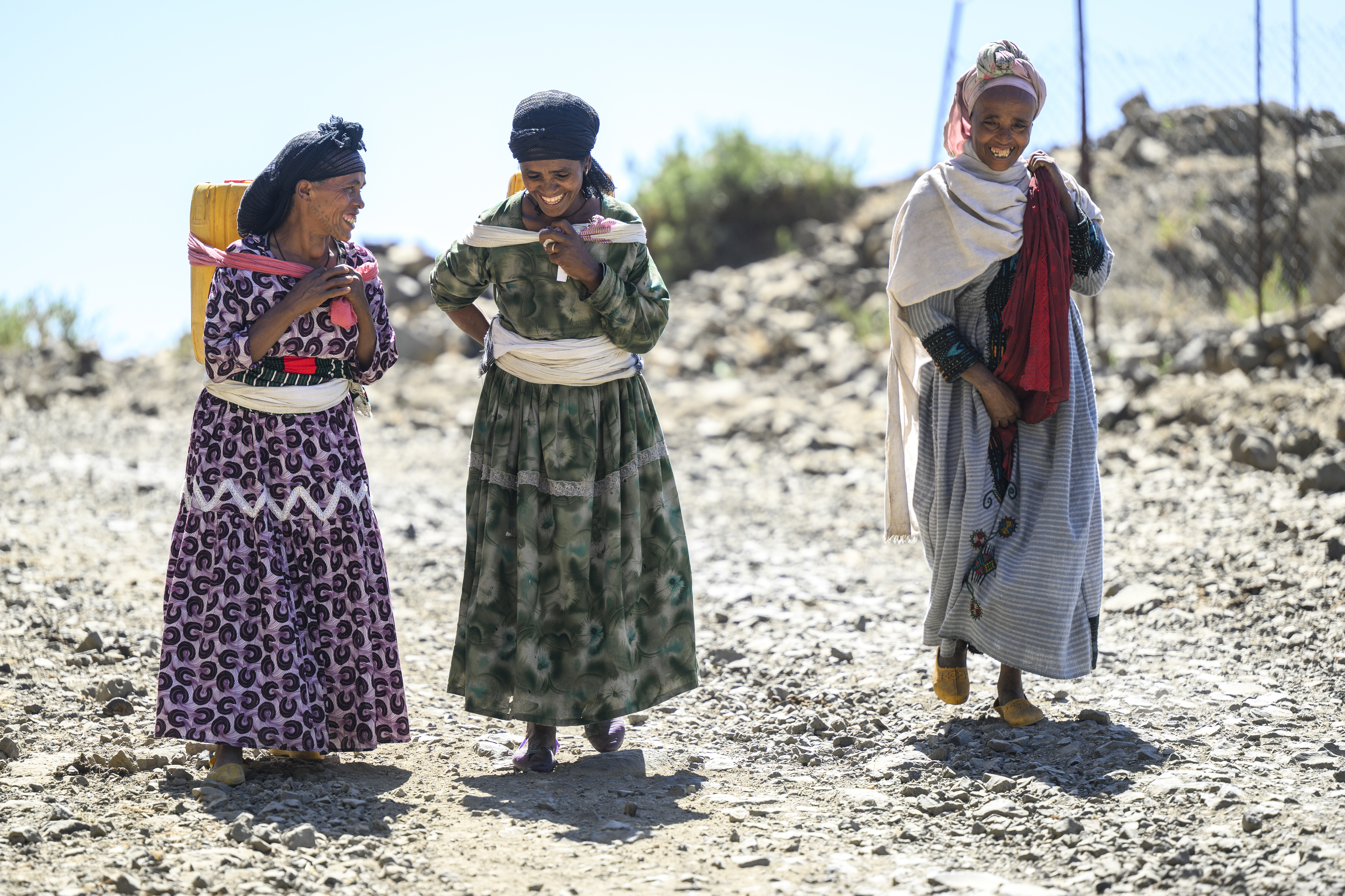 Tre kvinnor som vandrar på en väg. Alla tre ser glada ut. 