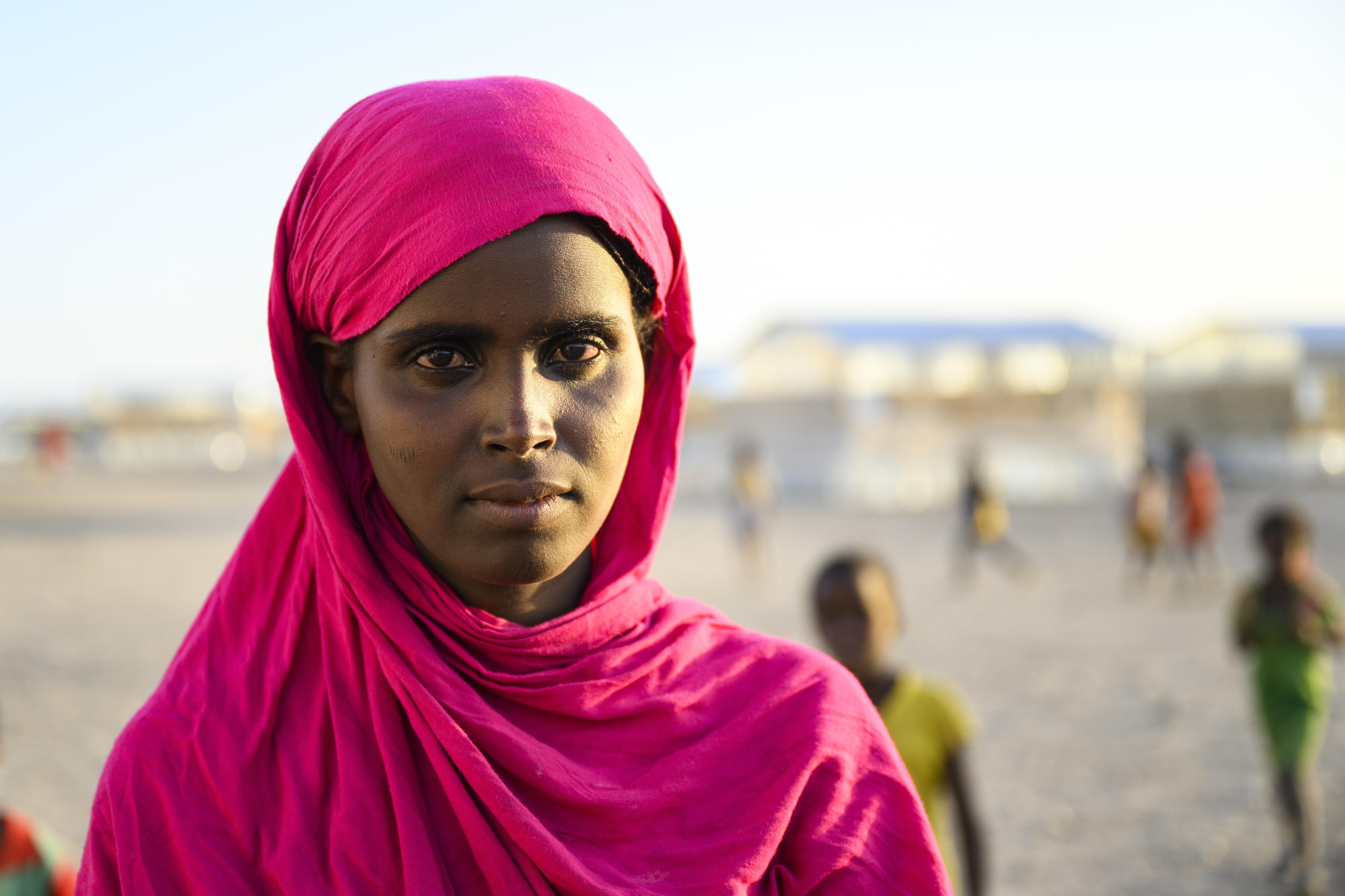 Kvinna med rosa sjal virad om huvudet.