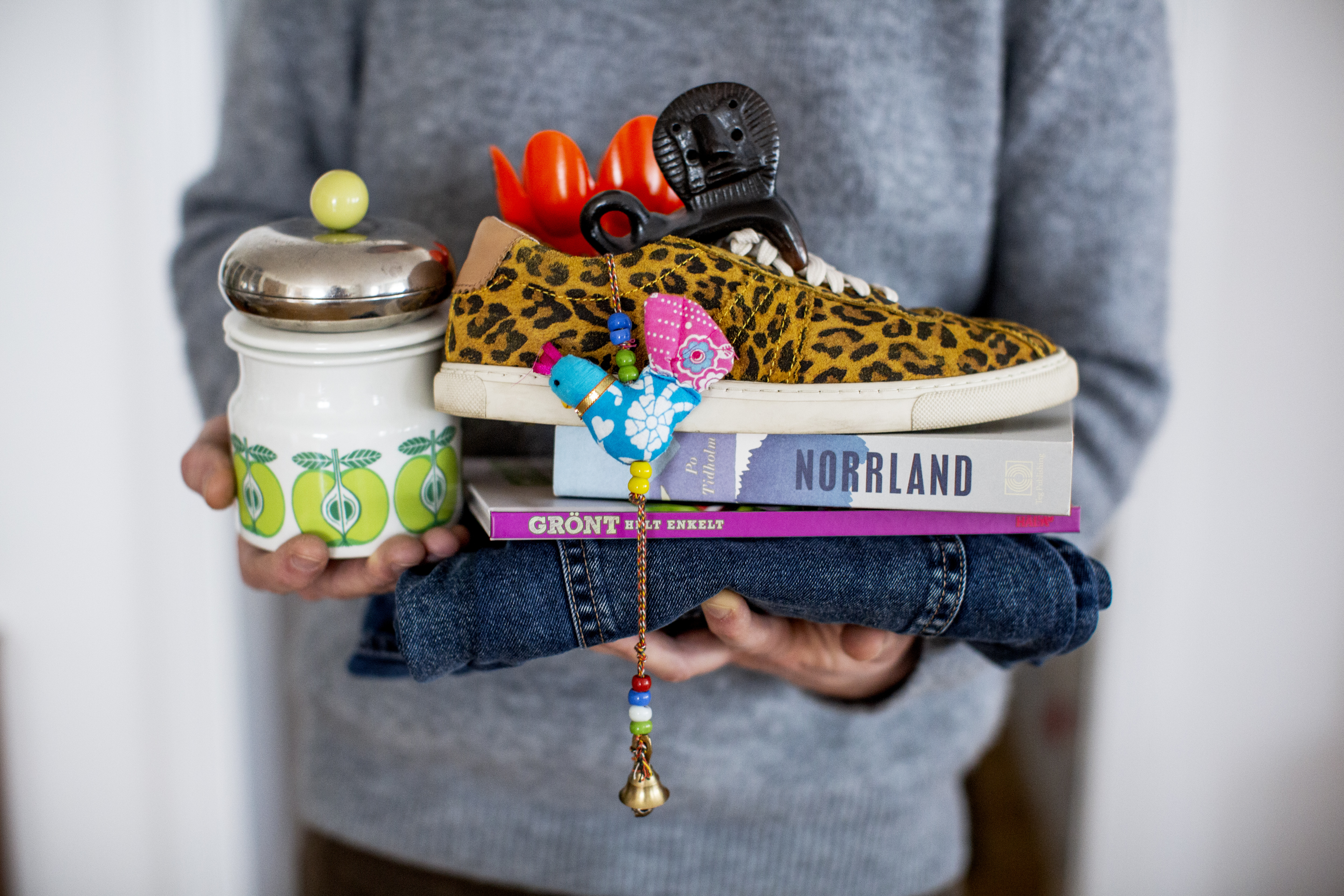 Person står och håller i kläder, böcker och saker.