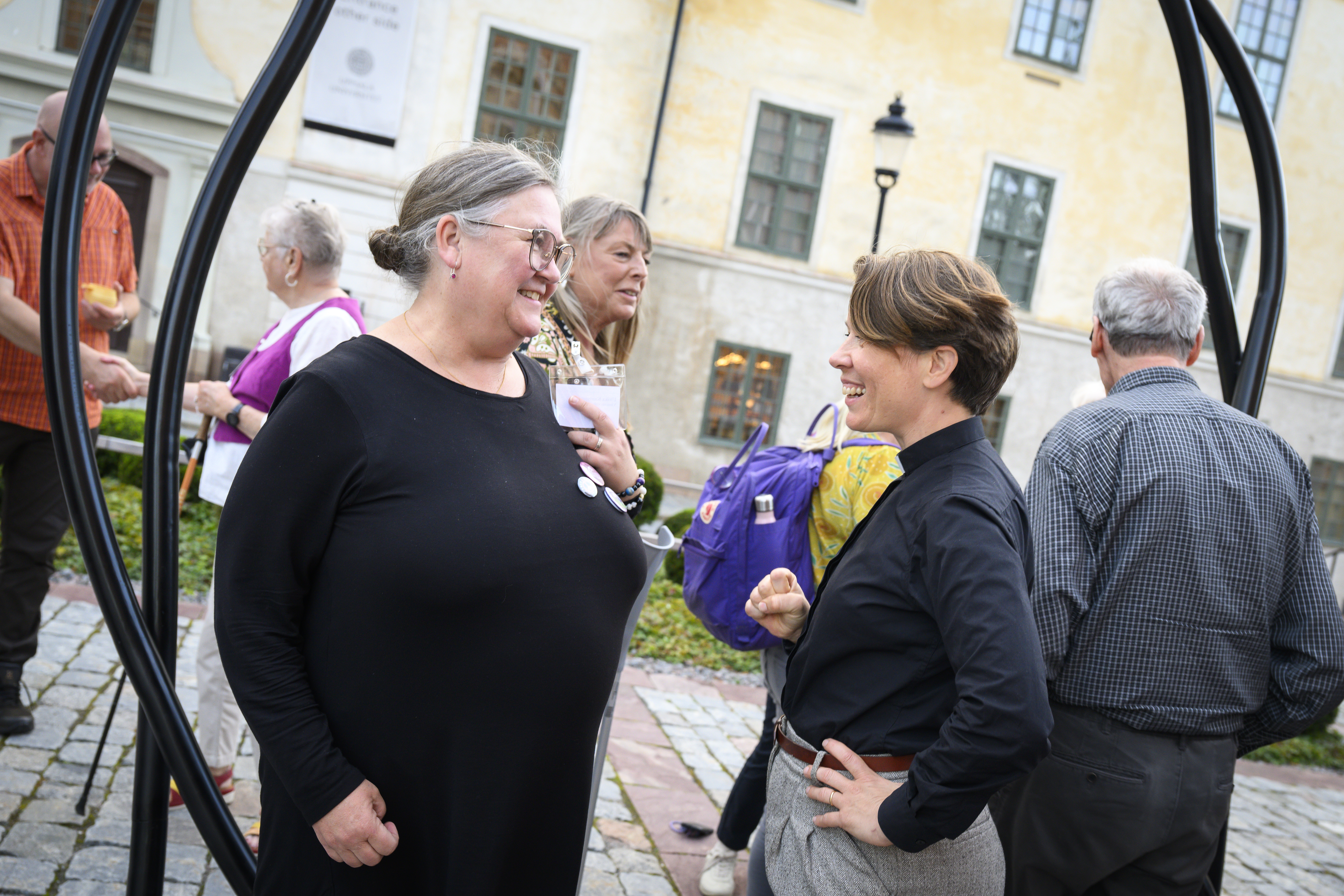 Två kvinnor samtalar i en grupp av människor.