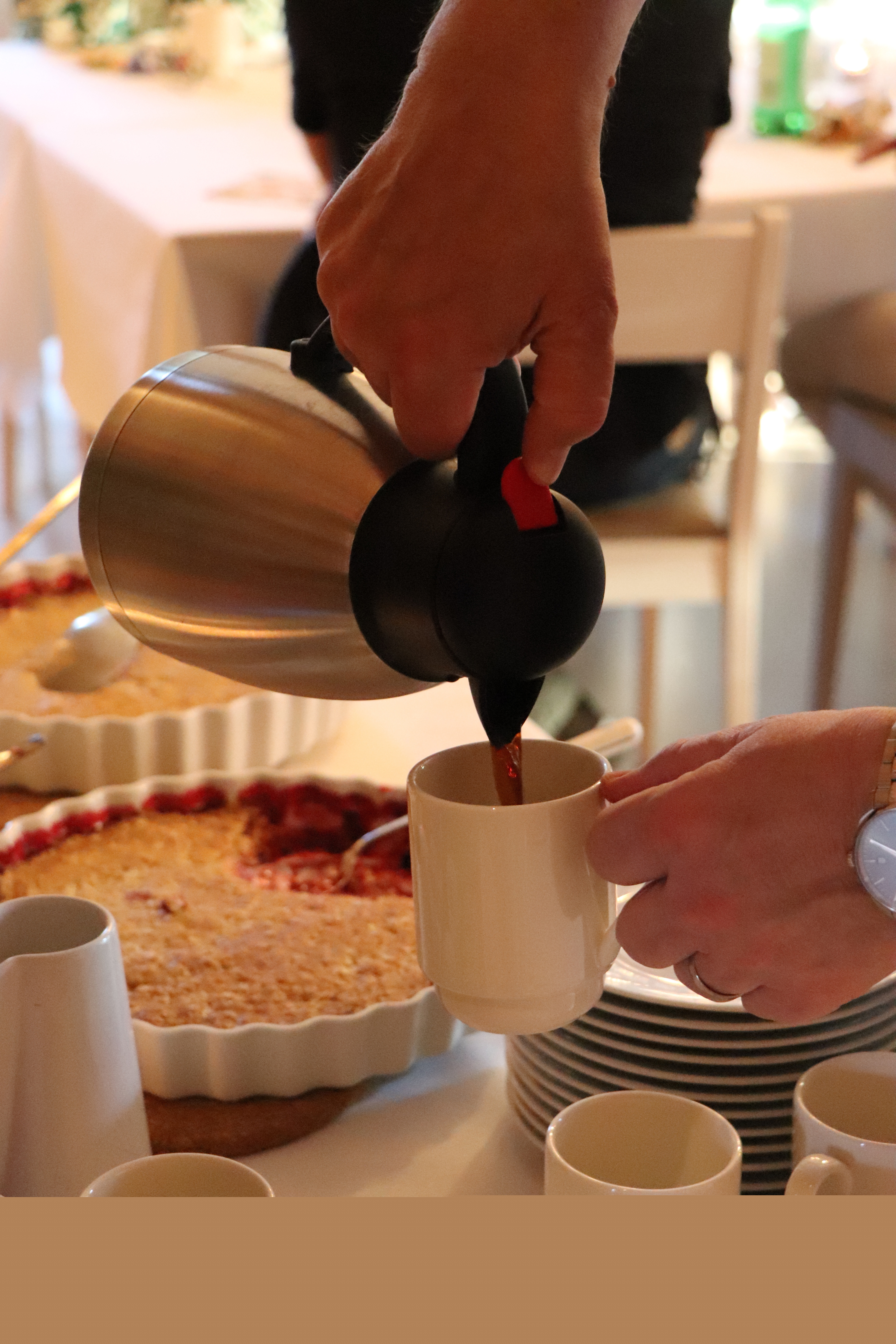 Vita dukar och blommor på borden, kaffe och paj serveras.