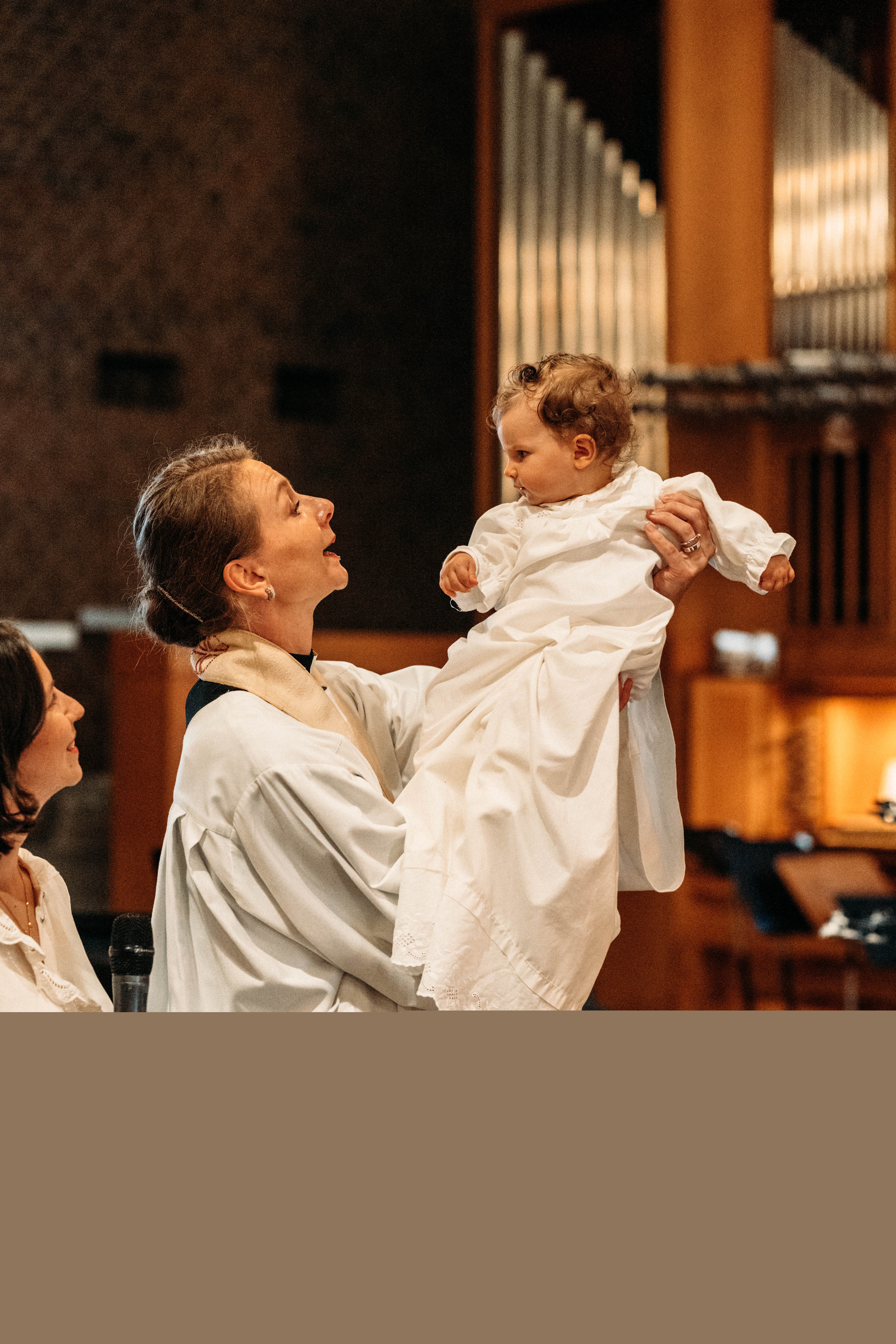 Ett barn döps omgiven av familj i en kyrka.