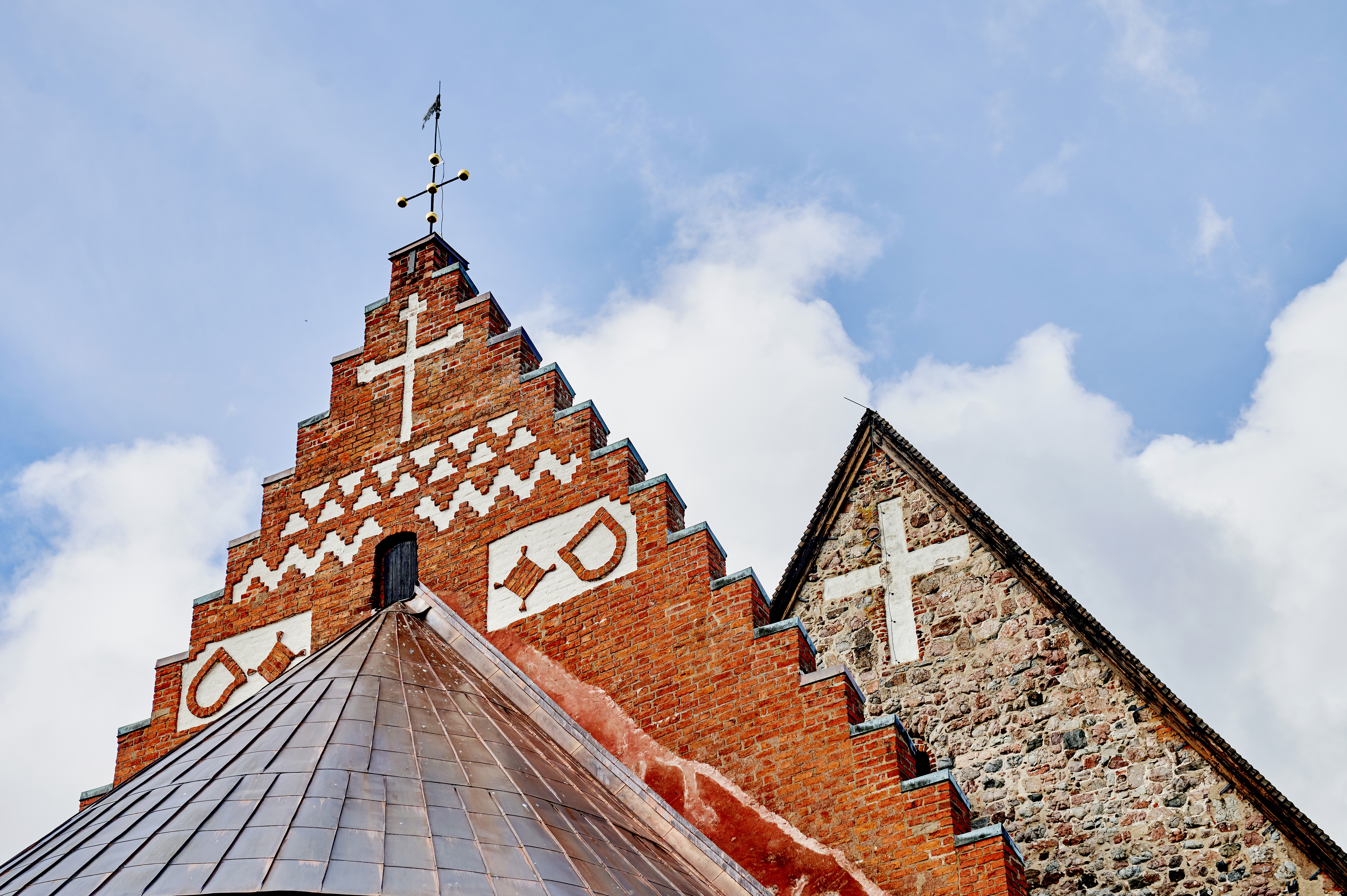 Delar av Gamla Uppsala kyrkas fasad med blinderingar i blickfånget.