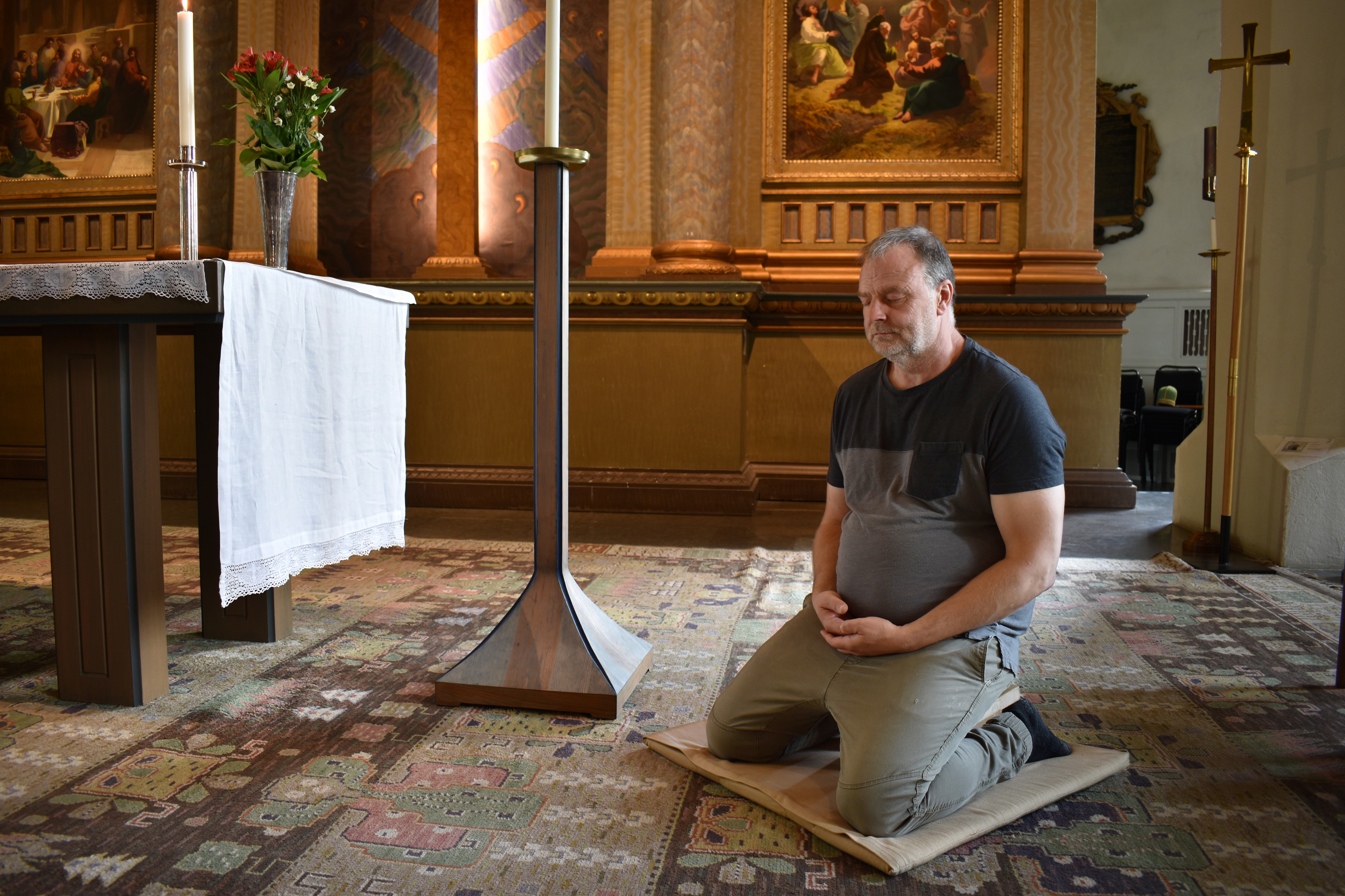 Man sitter och mediterar intill altaret i kyrka.