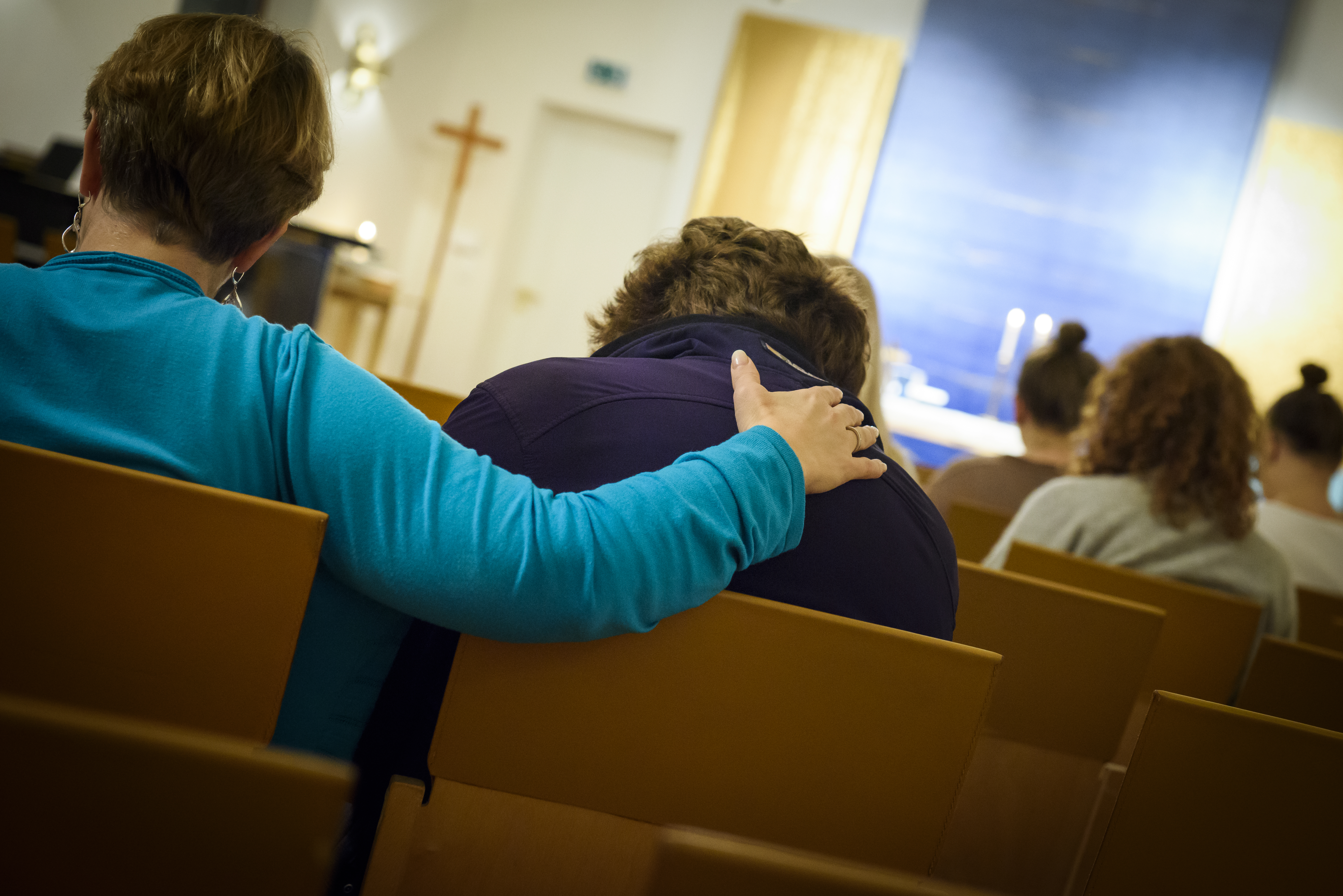 Lohduttava käsi naisen olalla.