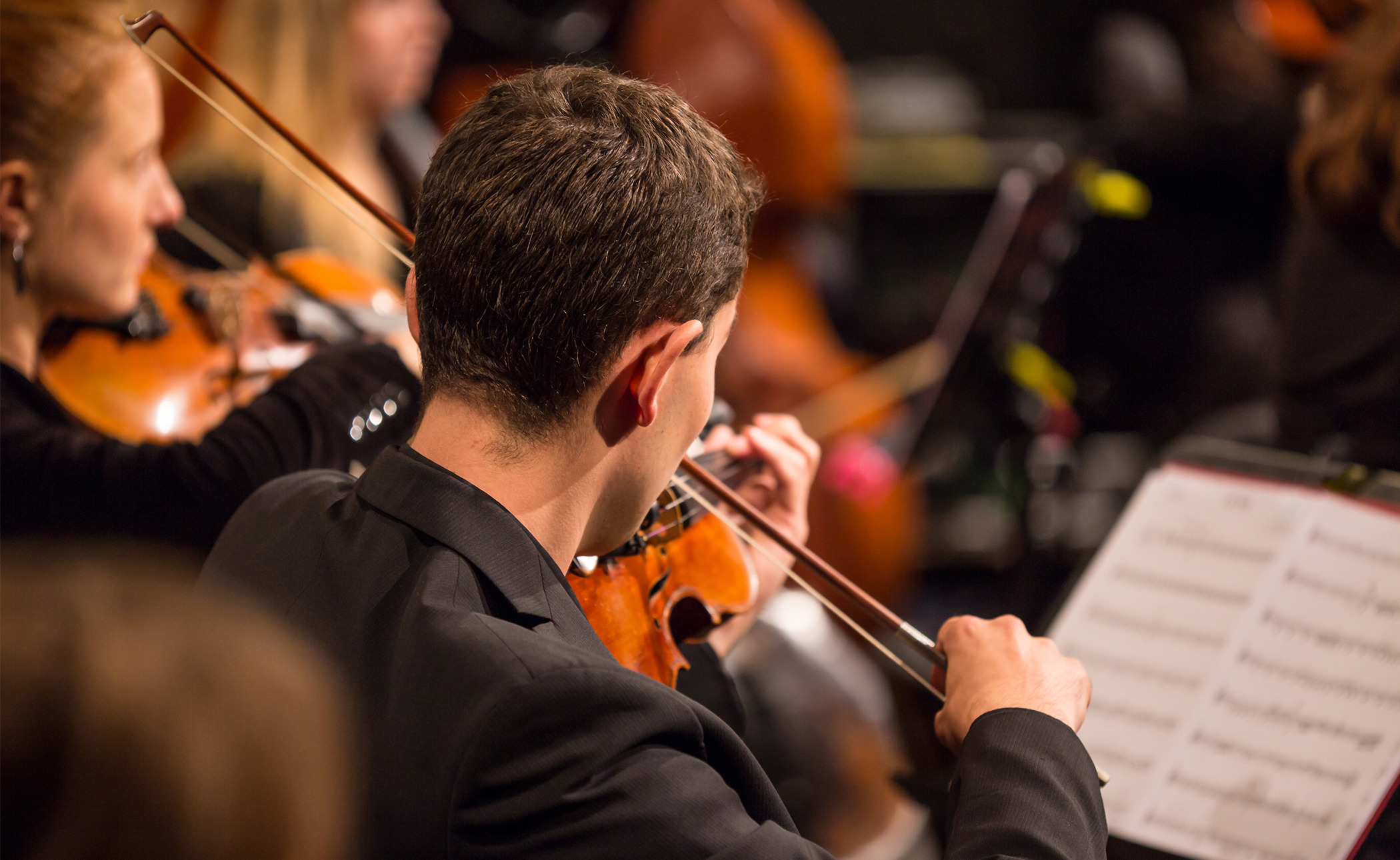 Musiker med varsitt stråkinstrument, troligtvis fioler, och ett nothäfte.
